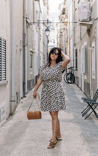 Portrait of attractive young woman standing in alley. summer dress, style, lifestyle.