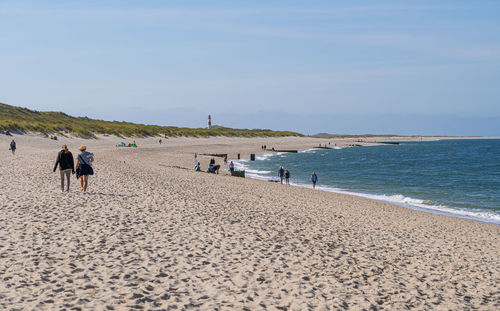 People walking on beach against sky