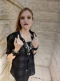 Portrait of young woman standing against wall