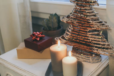 Gift boxes near lighted candles and christmas tree inside home. box with holiday ribbon with bows 