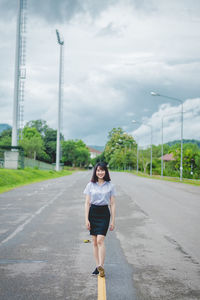 Full length of woman standing on road against sky