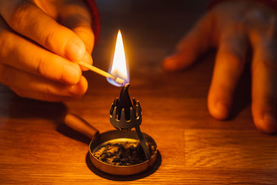 Close-up of hand holding lit candle