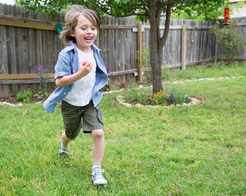 Full length of happy boy running on grass