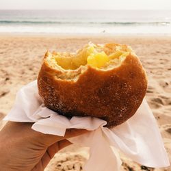 Close-up of hand holding sweet bun at beach