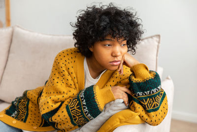 Portrait of young woman sitting on sofa at home