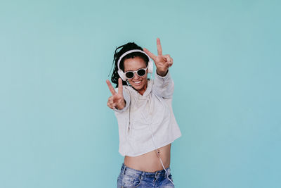 Portrait of man wearing sunglasses standing against white background