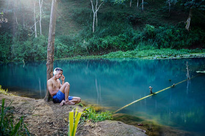 Man sitting in lake against trees in forest