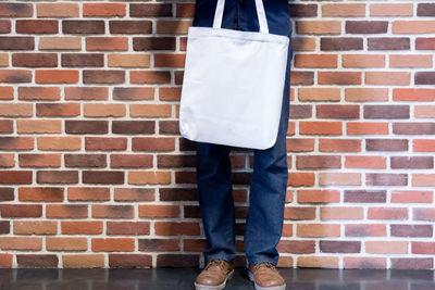 Low section of man standing against brick wall