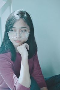 Close-up of young woman sitting against wall