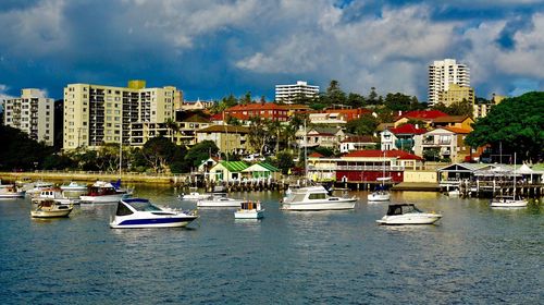 Sailboats moored in city by buildings against sky