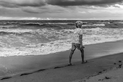 Full length of woman standing on beach against sky