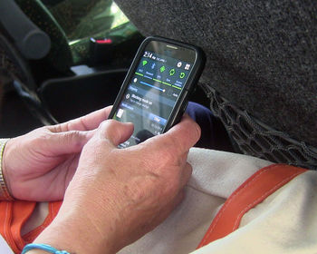 Midsection of man using mobile phone in car