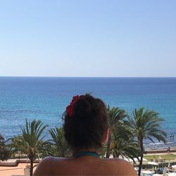 Rear view of woman standing on beach against clear sky