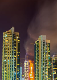 Low angle view of illuminated buildings against sky at night