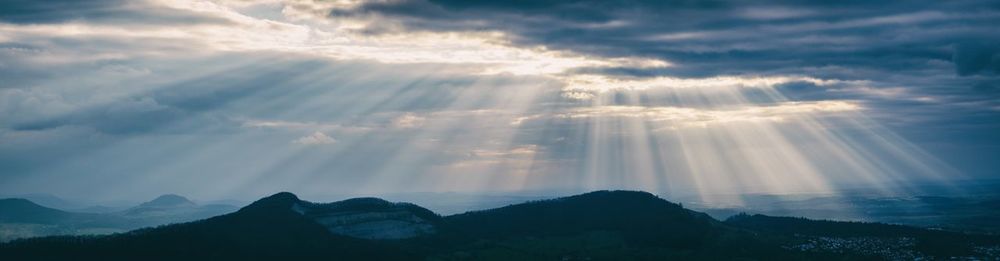 Sunlight streaming through clouds over mountains