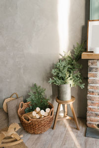 A basket for firewood by the fireplace and fir branches in a tin bucket. cozy atmosphere at home 