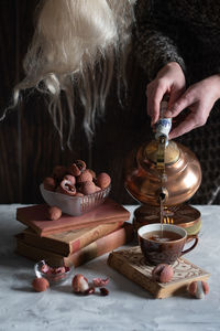 A woman pours tea from a copper teapot into a cup,still life with lychee,cozy