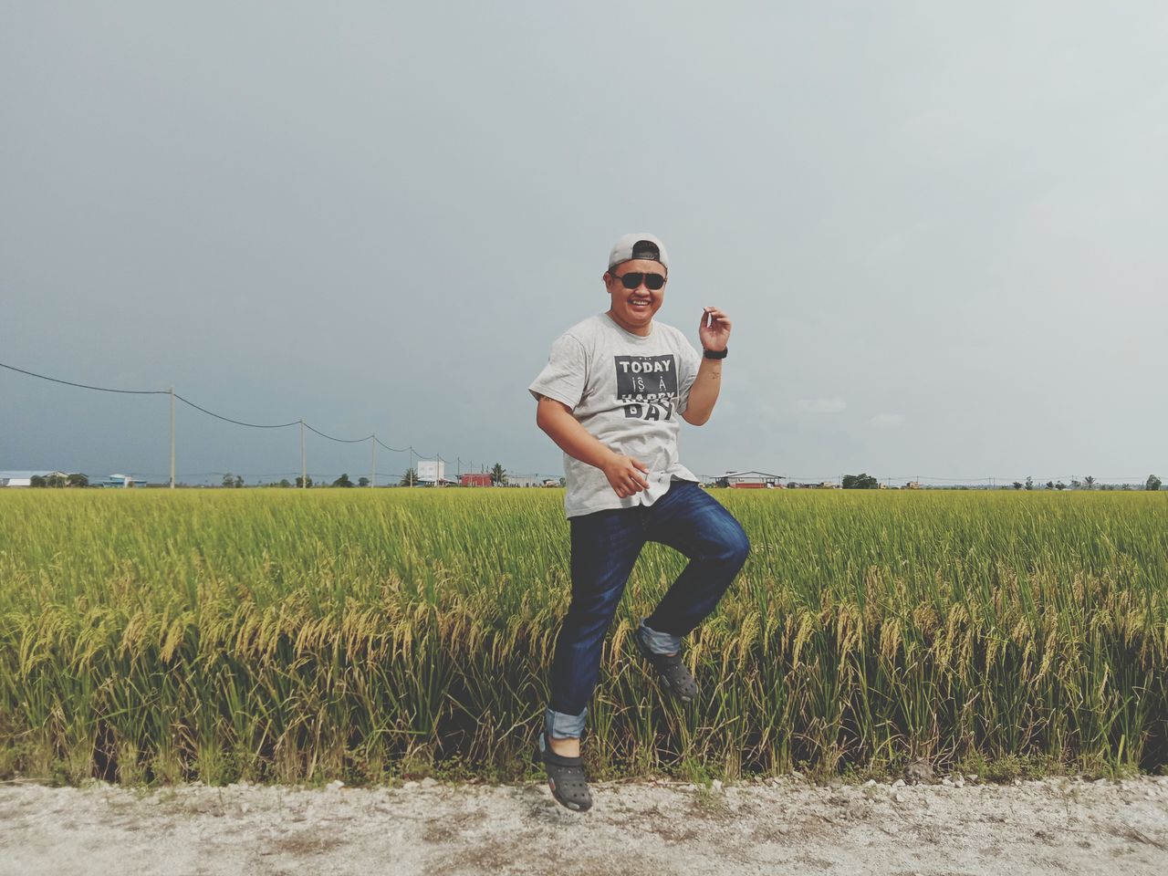 field, casual clothing, one person, land, real people, leisure activity, sky, front view, landscape, agriculture, plant, nature, farm, young adult, lifestyles, looking at camera, full length, growth, young men, rural scene, outdoors