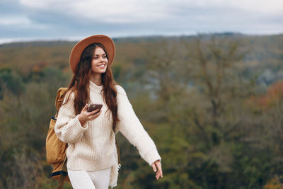 Young woman standing against trees