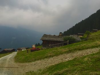 Houses on grassy field against cloudy sky