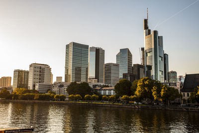 Buildings by river against sky in city