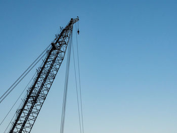 Low angle view of crane against clear blue sky