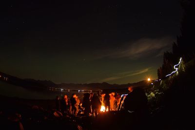 Rear view of people against sky at night