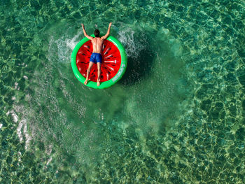 High angle view of man on inflatable watermelon in sea