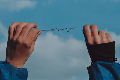 Low section of person holding hands against sky