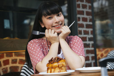 Portrait of smiling woman holding ice cream in restaurant