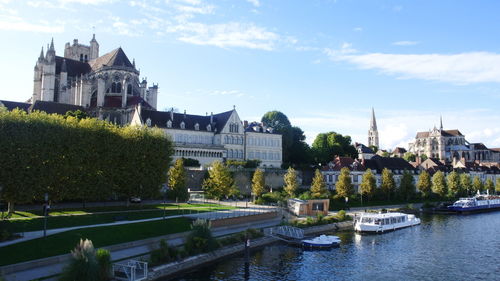 View of buildings by river against cloudy sky