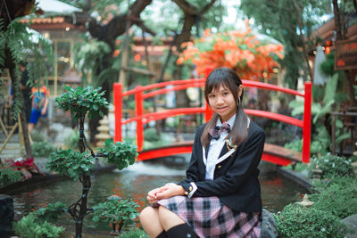 Portrait of woman sitting against plants