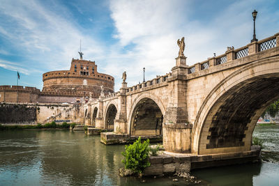 Arch bridge over river against sky
