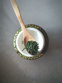 High angle view of herbs in wooden spoon over bowl