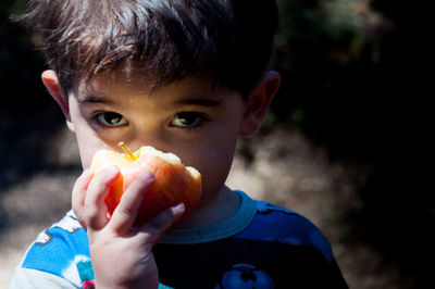 Close-up portrait of boy eating apple