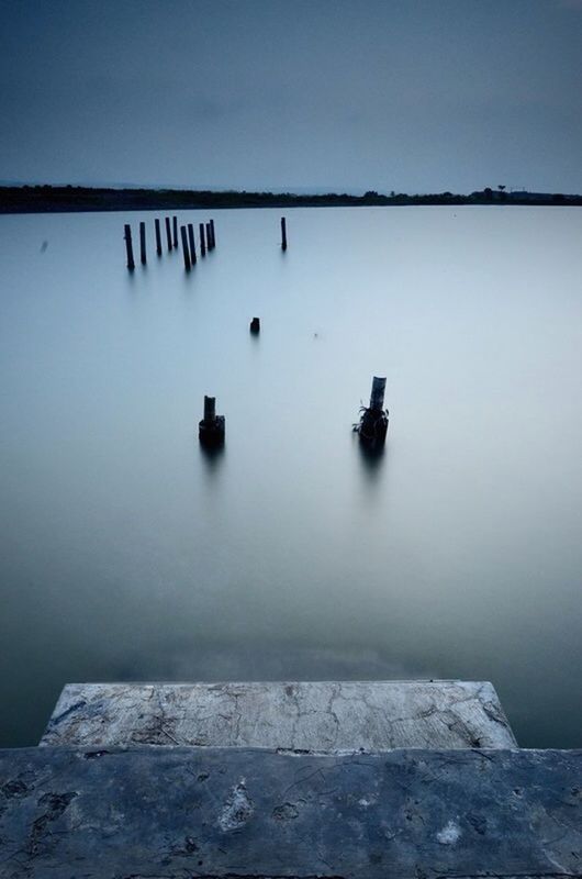 clear sky, copy space, water, sea, horizon over water, reflection, tranquility, tranquil scene, built structure, no people, nature, outdoors, day, wall - building feature, transportation, blue, architecture, nautical vessel, beauty in nature, calm