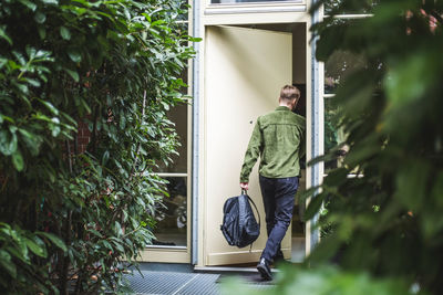 Male entrepreneur with bag entering in house