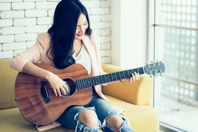 Full length of woman playing guitar