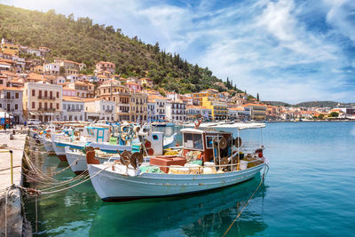 Sailboats moored on sea by city against sky