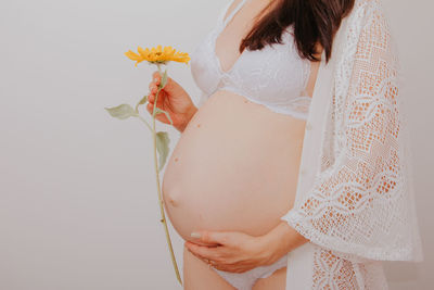 Midsection of woman holding umbrella against white background