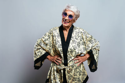 Portrait of young woman wearing sunglasses standing against black background