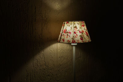 Close-up of illuminated lamp by wall