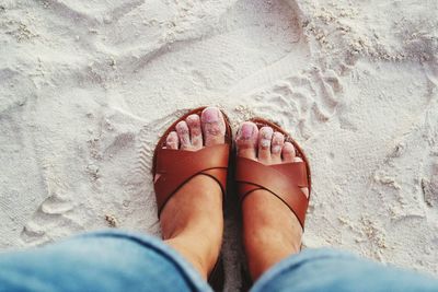 Low section of woman standing on sand at beach