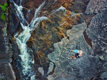 View of a couple on rocks at a beautiful river stream taken from drone