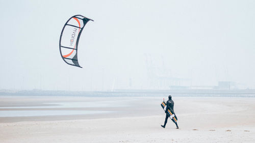 Man riding bicycle on beach against clear sky