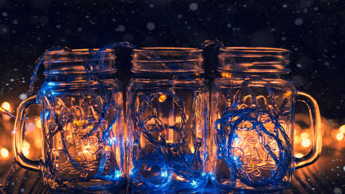 Close-up of illuminated string lights in jars on table