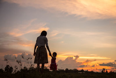 Mother and daughter against sky during sunset