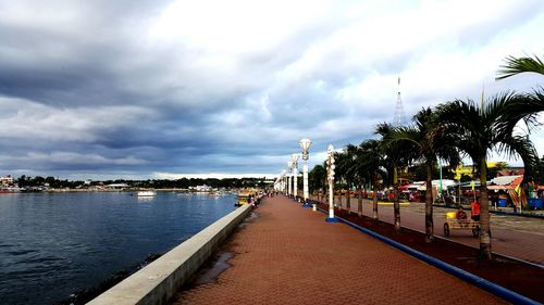 View of footpath against cloudy sky