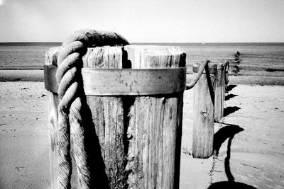 Wooden posts on beach against clear sky