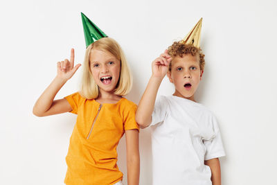 Portrait of smiling sibling party hat against white background